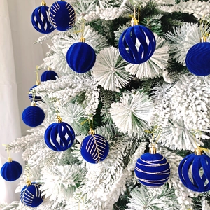 Gros plan de boules de Noël en velours bleu avec motifs dorés sur un sapin de Noël enneigé