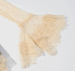 Gros plan des poignets en dentelle abricot avec broderie florale en maille fine