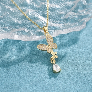 Gold butterfly necklace with micro-pave zircons and drop pendant on blue water texture