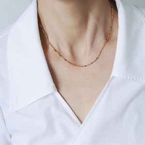 Detail of 18K gold plated titanium necklace with colorful enamel beads on a model