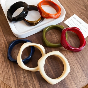 Close-up of colorful chunky acrylic bangles with wavy geometric edges on a tray