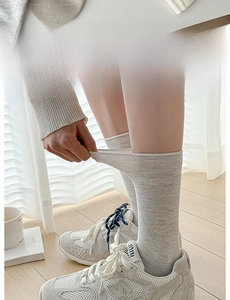Detail of light grey elastic mid-calf socks with widened comfort cuff for women