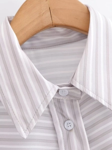 Close-up of grey and white striped shirt collar on wood hanger with button detail