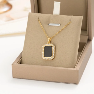 Detail of a gold rectangular pendant with black inlay and white zircon stones in a jewelry box