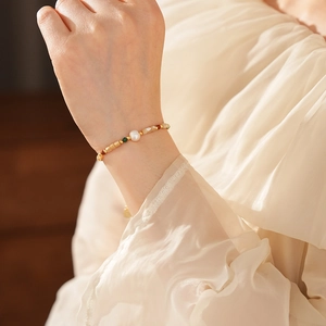 Détail du bracelet en perles plaqué or avec pierres naturelles sur le poignet d'une femme