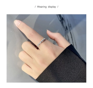 Wearing display of a silver anxiety ring with beads and sparkling stones on finger
