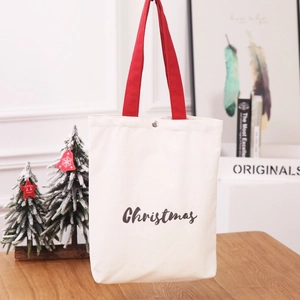 Christmas white canvas gift bag with red straps and festive lettering in a holiday setting