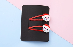Detailed view of two Christmas Santa Claus hair clips with red glitter on black card