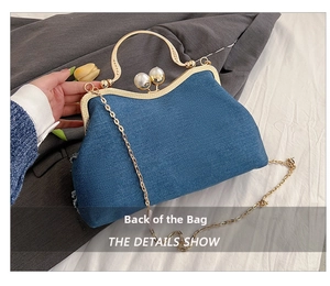 Detailed view of denim shell bag with large pearl clasp and gold wavy handle