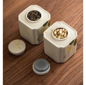 Close-up of ceramic tea canisters with hand-painted birds and airtight wooden lids