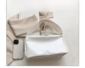 Size comparison of white leather tote bag with phone and book showing large capacity