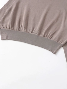 Détail macro du pull en maille taupe montrant l'ourlet côtelé et la texture fine