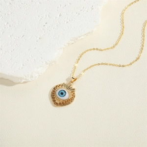 Golden necklace with heart-shaped evil eye pendant displayed on a white rock base