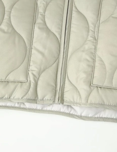 Detailed view of wave-quilted pattern and high-quality zipper on light gray padded jacket