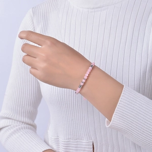 Detail of pink rose quartz Morse code bracelet worn by model on white knit background