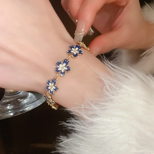 Detailed close-up of a floral enamel bracelet with gold plating on a model's wrist