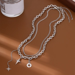 Silver layered necklace with star pendants and coin detail on vintage background