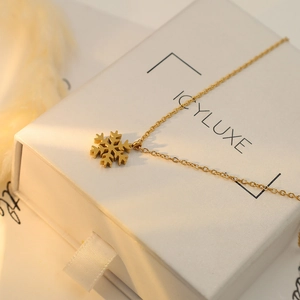 Close-up of 18k gold snowflake pendant on a fine chain inside a white jewelry box