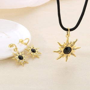 Parure étoile à huit branches dorée avec pierres noires et strass sur fond beige