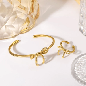 Elegant gold bow jewelry set with diamonds featuring an open bracelet and matching ring