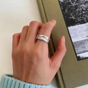 Detail of silver irregular wave ring with pave-set zircons on a green book background