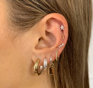 Detail shot of S925 silver stud earrings and gold hoops layered on an ear