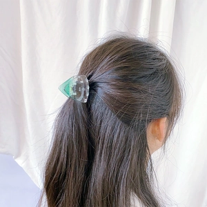 Close-up of a green gradient transparent triangular hair claw clip on a model's hair