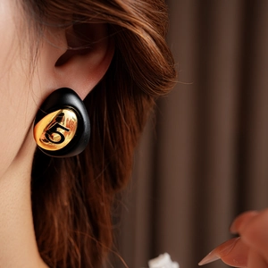 Close-up of gold plated drop earring with number 5 relief on a black base for women