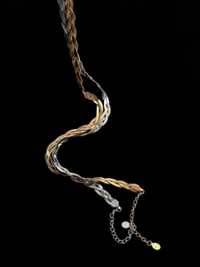 Detail of two-tone braided snake chain necklace with NO.1 engraved round tags