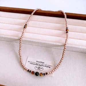 Vintage tiger eye pearl beaded necklace with an elegant pendant on beige jewelry display