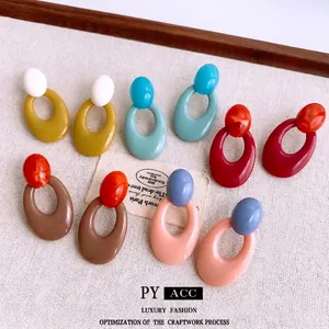 Set of five oval acrylic geometric drop earrings in retro contrasting colors on linen