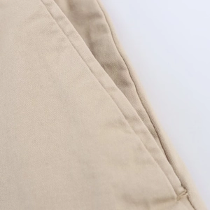 Detailed close-up of khaki cotton twill fabric texture and stitching on casual shorts