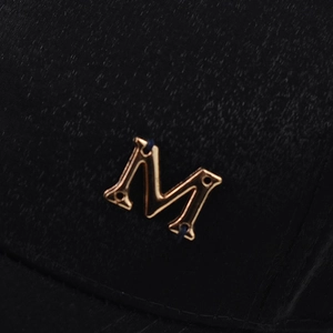 Dettaglio ravvicinato dell'emblema in metallo dorato lettera M su cappello nero