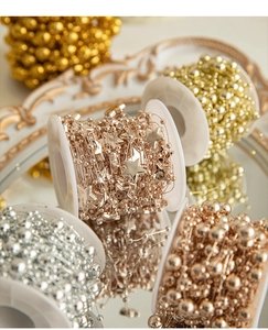 Macro shot of gold and silver Christmas star bead chains on an embossed mirror tray