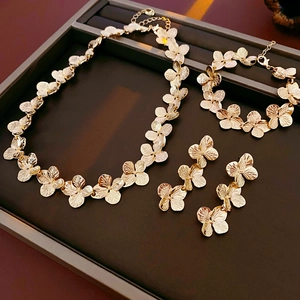 Golden flower jewelry set with necklace, bracelet and earrings in a dark display tray
