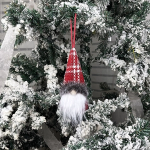 Christmas gnome hanging ornament with red plaid hat on snow-covered tree branch