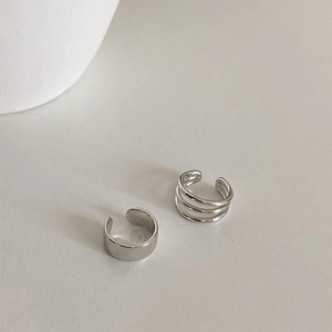 Detail of silver minimalist ear cuff set featuring smooth wide band and layered triple rings