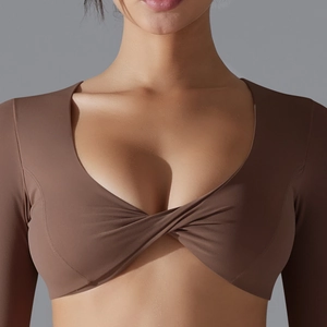 Primo piano del crop top a maniche lunghe marrone scuro con elegante nodo a incrocio frontale
