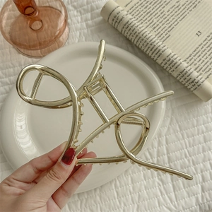 Large golden metal claw clip for women's hair styling with a sleek minimalist design