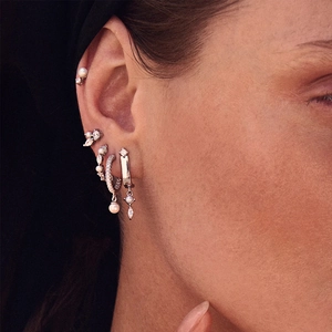 Detail of silver S925 earrings set with pearls and zircon on a model's ear