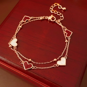 Vue détaillée du bracelet double rangée avec coeurs en émail sur fond en bois chic