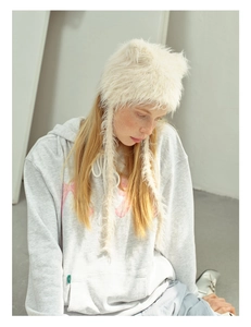 Detailed view of white faux fur cat ear hat with long braided tassels and soft plush texture