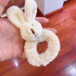 Detail of soft white plush bunny hair tie held in hand with fluffy texture and cute design