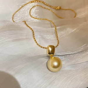 Détail d'une chaîne torsadée plaquée or 18 carats avec perle champagne sur soie blanche