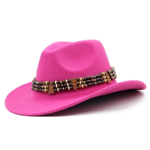 Détail d'un chapeau de cow-boy rose en feutre avec ruban ethnique perlé sur blanc