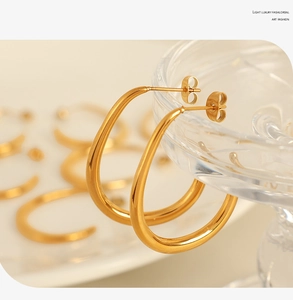 Macro shot of minimalist gold oval earrings hanging on a transparent glass jewelry tray