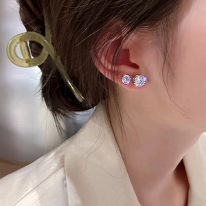 Pair of sparkling round zircon stud earrings in silver shown worn on a model's ear