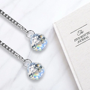Sparkling crystal ball pendant on silver chain with faceted spherical design on marble