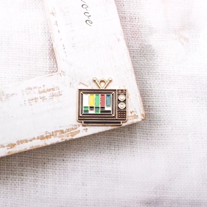 Macro view of a retro TV enamel charm with colorful stripes on a rustic wood background