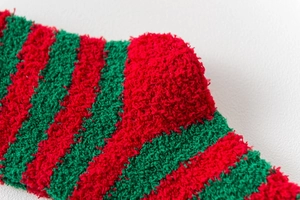 Detailed macro view of soft red and green striped coral fleece Christmas sock fabric